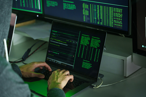 Hacker's hands using laptop computer to code program. Focus on keyboard