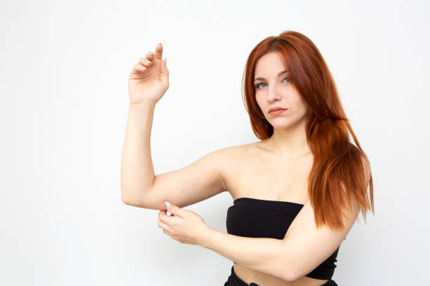 Woman pinching the skin beneath her arm to control bat wings Woman pinching the skin beneath her arm to control fat and excess skin like bat wings or bingo wings bingo wings stock pictures, royalty-free photos & images