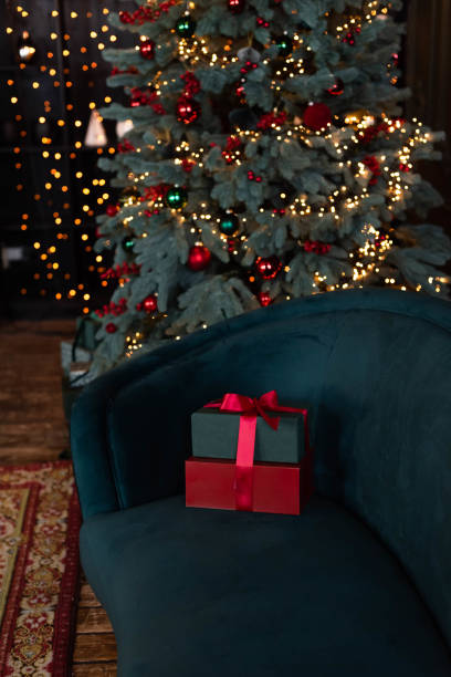 istock The gift boxes on a dark blue velvet sofa near a Christmas tree 1450585619
