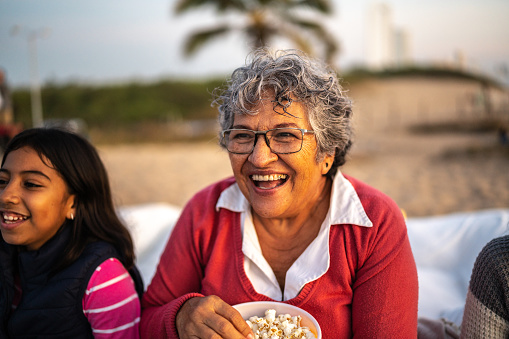 Senior woman eating popcorn at the outdoors cinema
