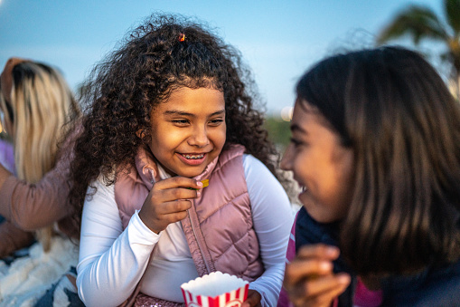 Girls eating popcorn and talking at the outdoors cinema