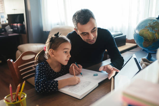 padre ayudando a su hija con su tarea - educación en el hogar fotografías e imágenes de stock