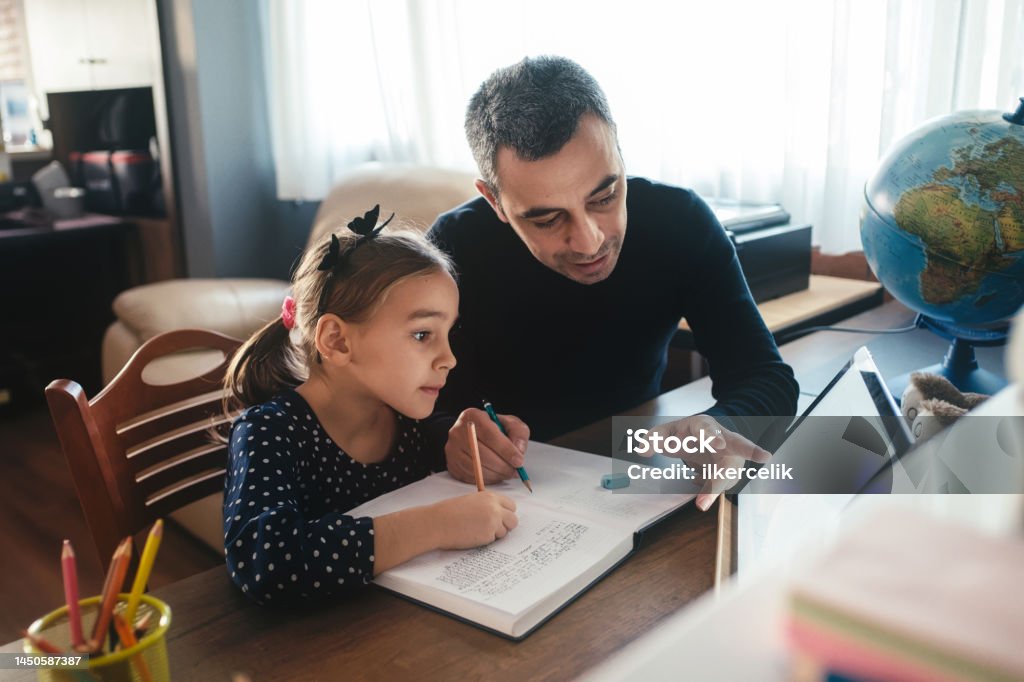 Father helping his daughter with her homework Child Stock Photo