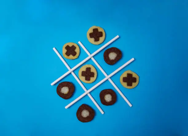 Tic tac toe game with freshly baked cookies on blue background top view