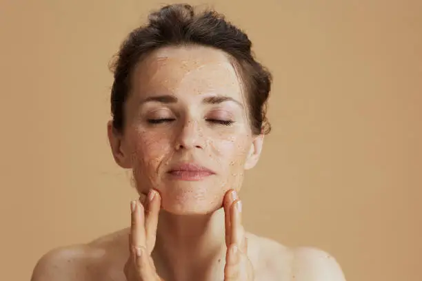 Photo of modern woman with face scrub isolated on beige