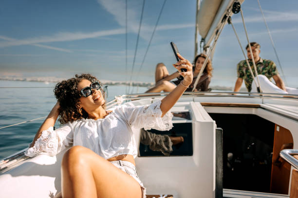 istock Young woman taking selfie with mobile phone on sailboat 1450589921