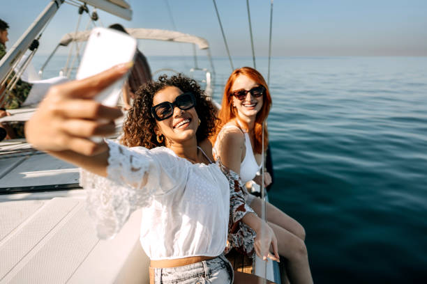 Selfie time! Female friends taking selfie while riding on a yacht together yacht selfie stock pictures, royalty-free photos & images