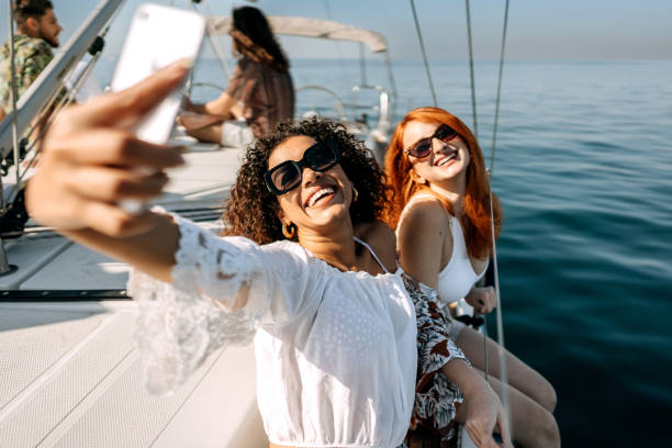 Selfie time! Female friends taking selfie while riding on a yacht together slow motion photos stock pictures, royalty-free photos & images