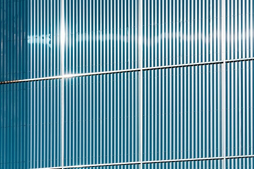 Corrugated Steel Wall of Warehouse Building against blue sky background with sunlight and shadow on surface