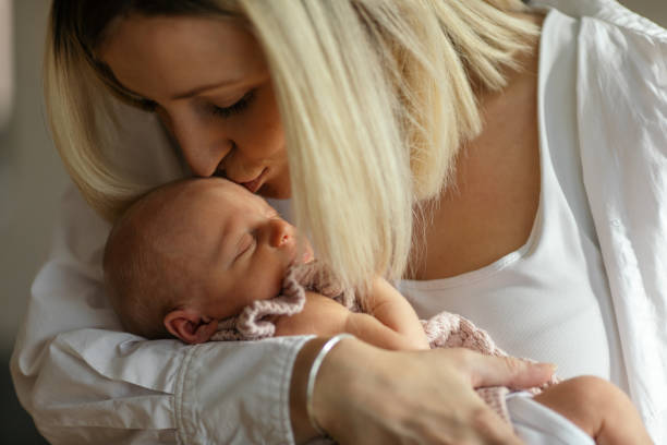 istock Newborn baby sleeping in her mother's arms 1450594367