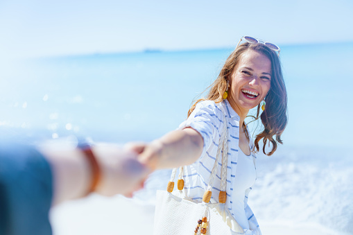 happy elegant woman at the beach in white striped shirt and shorts having fun time.