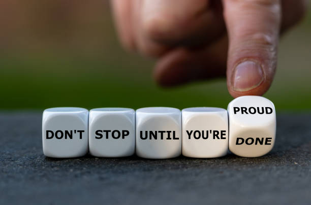 Hand turns dice and changes the expression 'don't stop until you are done' to 'don't stop until you are proud' . stock photo