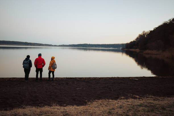 istock Friends staring by a lake at sunset 1450615754