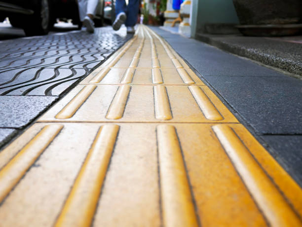 istock Low angle perspective view of Pedestrian walking with Yellow Blind guide Tactile paving for disability, and blind people, texture on tiles for handicap, selective focus, footpath 1450615822