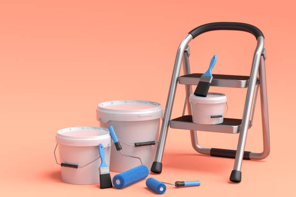 Set of metal can or bucket with paint roller, brush and folding ladder on orange stock photo