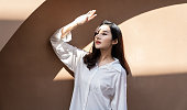 Portrait of young beautiful asian woman traveler hands protect face from sun light in fresh summer time. Happy cheerful asian girl in summer. Beauty sunscreen skin care make up model concept
