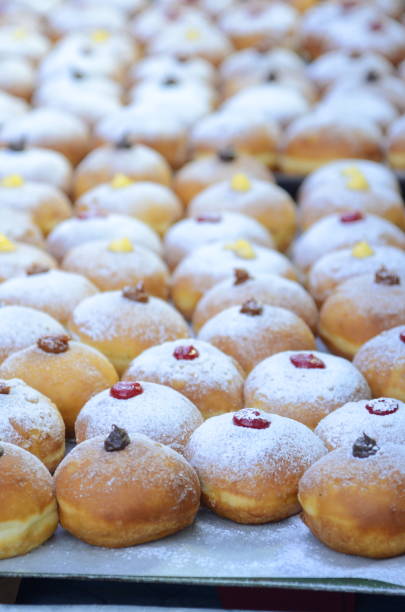 Sufganiyah - donuts are a symbol of the jewish holiday hanukkah. Fresh donuts with chocolate, jam at the bakery display for celebration. Sufganiyot - Israeli Donuts. Selective focus. Symbol of sweet Hanukkah donut - Sufganiyah. hanukkah shopping stock pictures, royalty-free photos & images