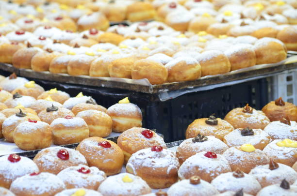 Sufganiyah - donuts are a symbol of the jewish holiday hanukkah. Fresh donuts with chocolate, jam at the bakery display for celebration. Sufganiyot - Israeli Donuts. Selective focus. Symbol of sweet Hanukkah donut - Sufganiyah. hanukkah shopping stock pictures, royalty-free photos & images