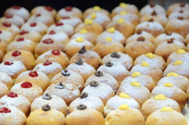 Sufganiyah - donuts are a symbol of the jewish holiday hanukkah. Fresh donuts with chocolate, jam at the bakery display for celebration. Sufganiyot - Israeli Donuts. Selective focus. Symbol of sweet Hanukkah donut - Sufganiyah. hanukkah shopping stock pictures, royalty-free photos & images