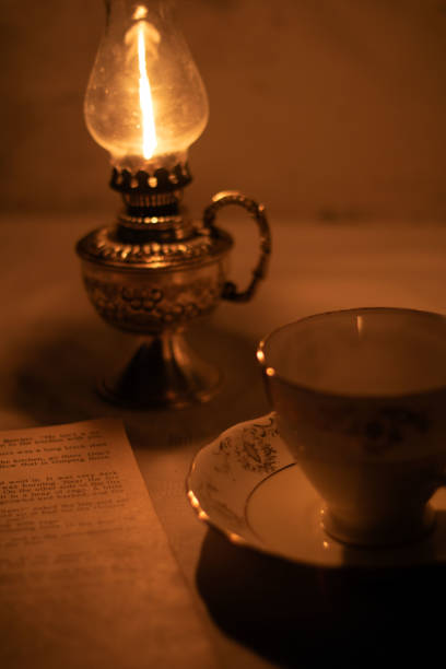 istock photo kerosene lamp and an old book with an empty cup on the table 1450619220