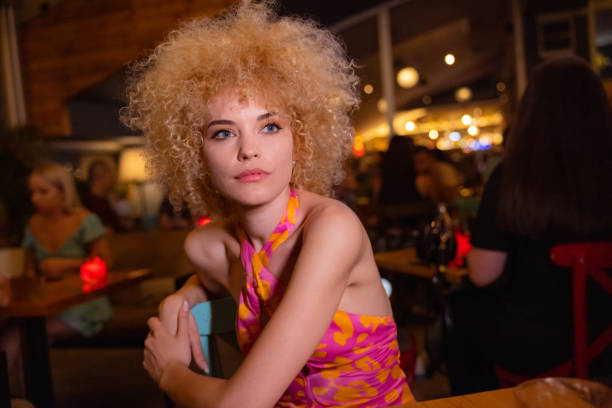 Urban and confident young Caucasian woman Portrait of confident and beautiful young Caucasian woman with curly blonde hair enjoying nightlife seduction stock pictures, royalty-free photos & images