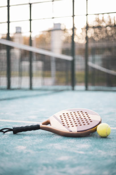 una raqueta de pádel y una pelota apoyada en el suelo. concepto de pádel. - tennis in a row team ball fotografías e imágenes de stock