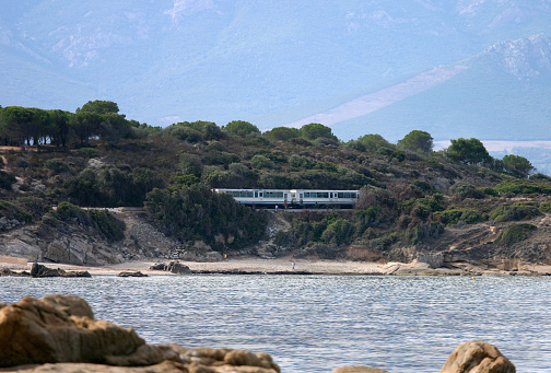 The Haute-Corse Beach Train is actually a  shuttle tramway serving 18 stops between Calvi and L'île Rousse in the north of the Mediterranean Island of Corsica in the Balagne region. Besides the towns and villages the railcar stops for walkers and hikers and for access to all the superb beaches along this stretch of scenic coastline. The railcar that has stopped here is for holidaymakers to visit the beach, Lumio, Plage de L'Arinella. After the multiple stops for Calvi and Lumio beaches, halts include Sant Ambroggio, Algagola, Marine de Davia, Bodri Plage and finally L'île Rousse carefully hugging the coastline as it traverses the Maquis.