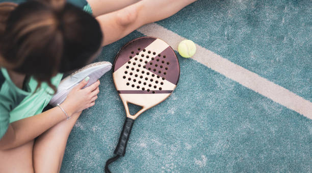 ein mädchen streckt ihr bein auf dem boden eines paddle-tennisplatzes, der schläger ist daneben, ansicht von oben. copyspace. - tournament bracket fotos stock-fotos und bilder