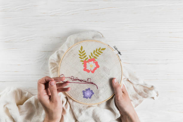 istock Woman doing handicraft embroidery work on white wooden background. 1450633855