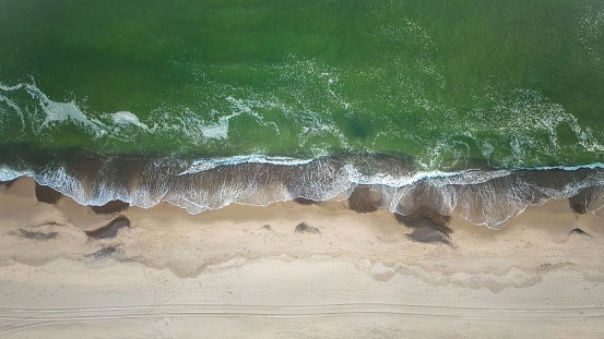 A aerial top view of the Danish coast on the north Sea with a sandy beach and hitting waves