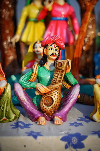 Beautiful handmade dolls of miniature folk musicians performing in a band of classical Indian music is displayed in a shop for sale in blurred background. Indian art and handicraft.