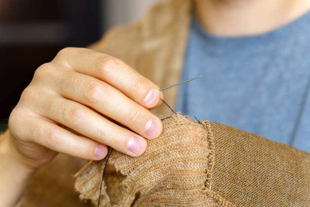 istock Mending clothes. A man is engaged in sewing. Household chores. Selective focus 1450639941