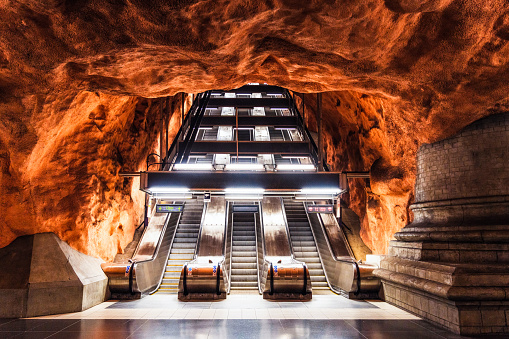 The distinctive illuminated rock surrounding the escalator leading up from the subway platform level at Rådhuset subway station in Stockholm.
