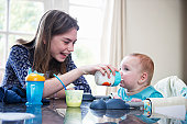 Girl feeding baby brother at table