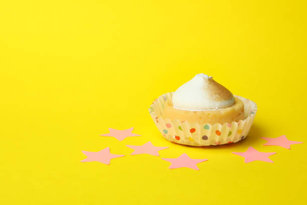 Lemon cupcake and pink stars on yellow background