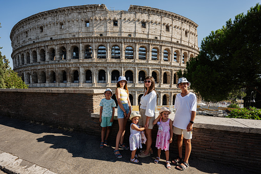 Mother with five kids pose against Colosseum in the old city center of Rome, Italy.