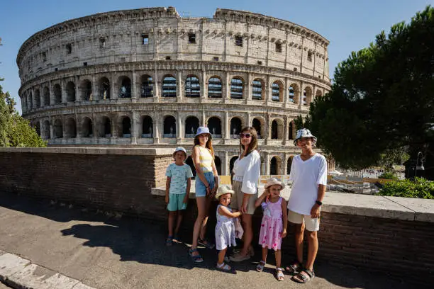 Photo of Mother with five kids pose against Colosseum in the old city center of Rome, Italy.