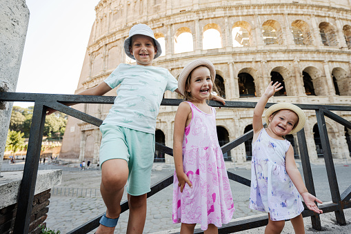 Three funny kids against Colosseum in the old city center of Rome, Italy.