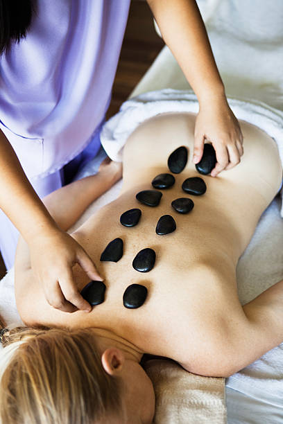 woman having hot stone massage in spa - massage therapist stone spa treatment working ストックフォトと画像