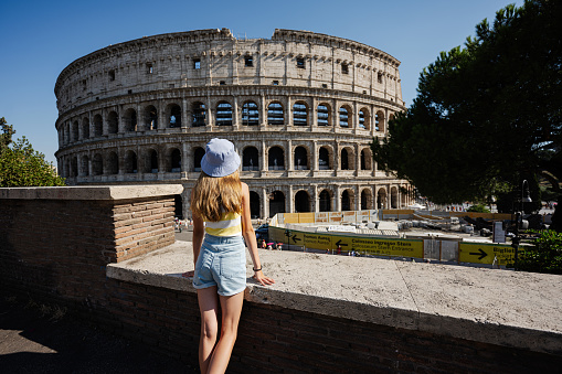 Back of girl tourist enjoy view Colosseum in the old city center of Rome, Italy.