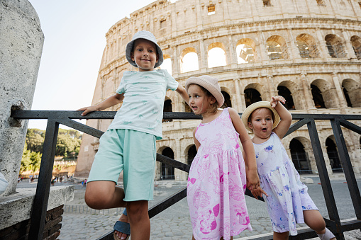 Three funny kids against Colosseum in the old city center of Rome, Italy.