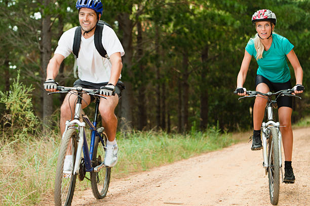 coppia andando in mountain bike su strada in terra battuta - journey footpath exercising effort foto e immagini stock