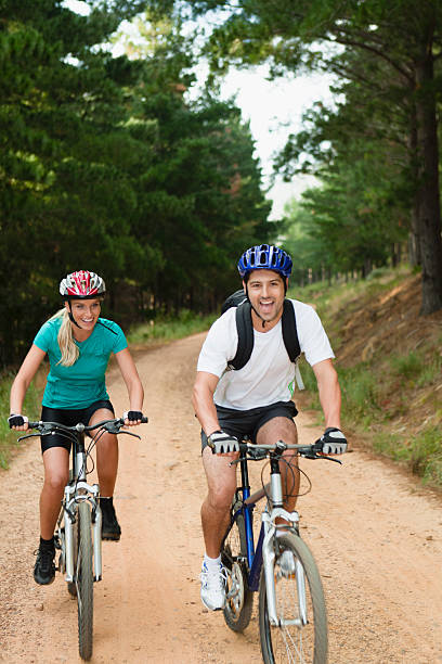 casal de mountain bike na dirt road - journey footpath exercising effort - fotografias e filmes do acervo