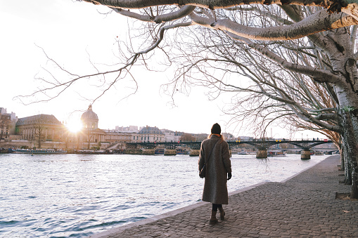 Woman walks along  Seine river in Paris, winter season December