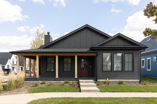 Elmhurst, IL, USA - September 26, 2022: A black ranch home with steps leading to a covered front porch with wood pillars.