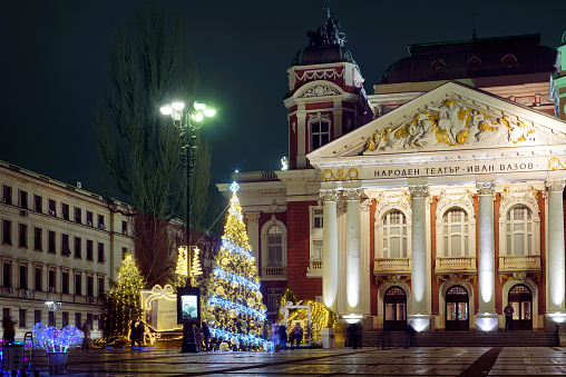 Outdoor Christmas tree and Christmas lights at night,  in front of National theater of Bulgaria in Sofia City garden.