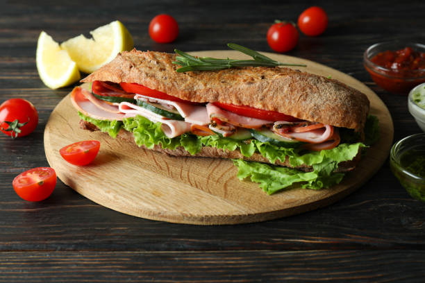 istock Board with ciabatta sandwich and ingredients on wooden table 1450654819
