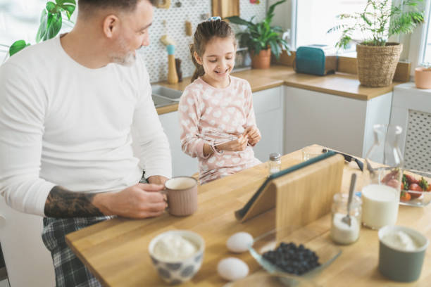 istock Happy father and daughter making breakfast in the kitchen. 1450656086