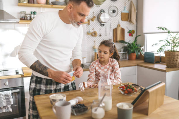istock Happy father and daughter making breakfast in the kitchen. 1450656408
