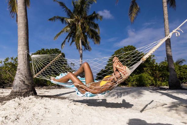 istock Happy woman sunbathing in hammock on the beach. 1450657098